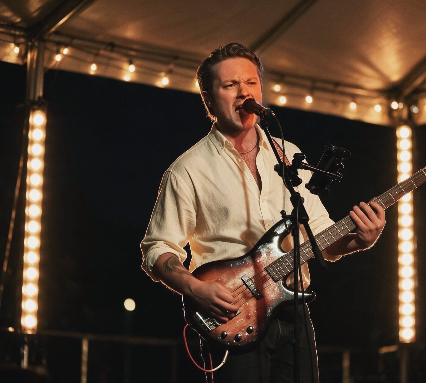 Voulez Groove bassist performing live under string lights
